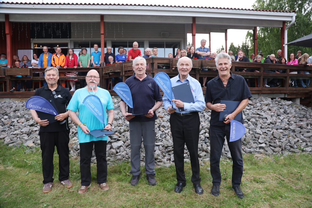 Kuvassa Suomi meloo viirillä ja kunniakirjalla palkitut Juhanni Holm Welhonpesä, Erkki Lappi, Antero Rossi, Tuomo Jantunen, Jouko Kivimetsä. Kuvasta puuttuu palkittu Björn Lehtinen Bear & Water